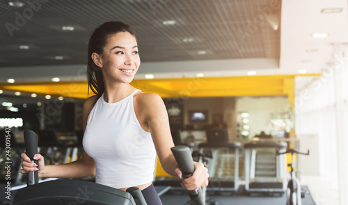 Fit woman exercising on cross trainer in gym photo