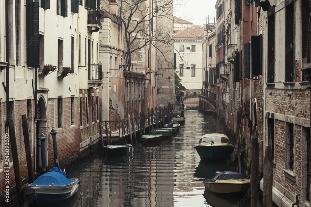 Morning view on narrow water canal with  rows of boats floating along the walls of houses in Venice, Italy