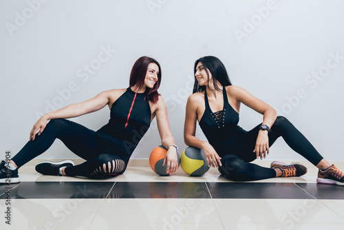 Athletic young women training with medball at gray background. Crossfit center. photo