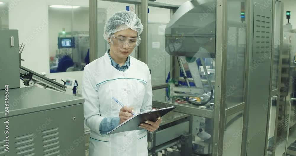 Pharmaceutical Factory Worker. A female technician is monitoring the process. Pharmaceutical Factory Worker. A female technician is monitoring the process.