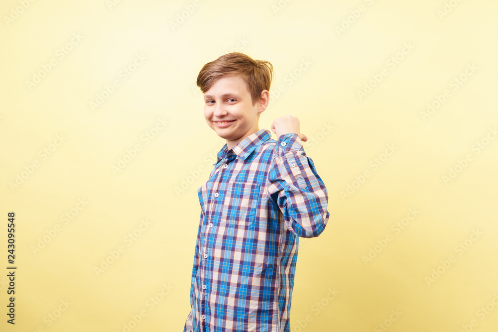smiling laughing boy pointing to object or text behind his back. advertisement or product placement, banner or poster template, emotion facial expression, people reaction smiling laughing boy pointing to object or text behind his back. advertisement or product placement, banner or poster template, emotion facial expression, people reaction