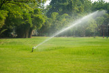 Automatic Garden Lawn sprinkler in action watering grass with sunny in the morning. - Image