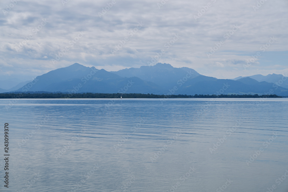 Beautiful lake and mountain landscape on cloudy day - blue colors - mirror reflections - Germany - Chiemsee