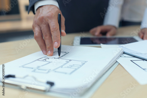 Real-estate agent showing house plans on electronic tablet.