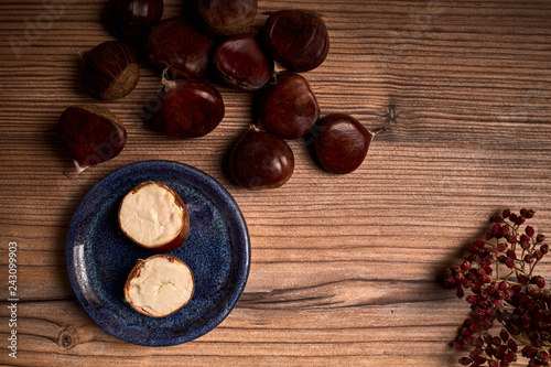 group of tasty chestnuts next to a bowl on an old wooden board 