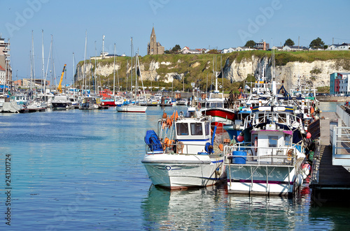 Fishing boats in the port of Dieppe and the church Notre Dame in the background on the cliffs