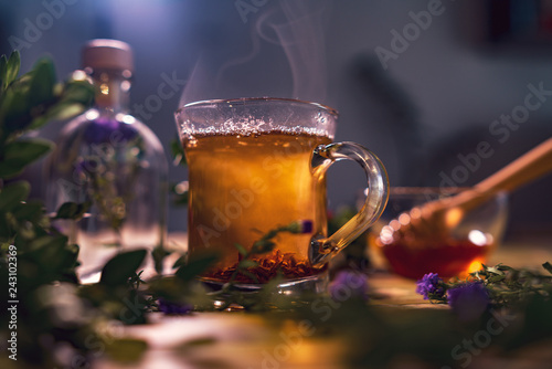 Black tea in a transparent mug, violet flowers, beautiful dark b