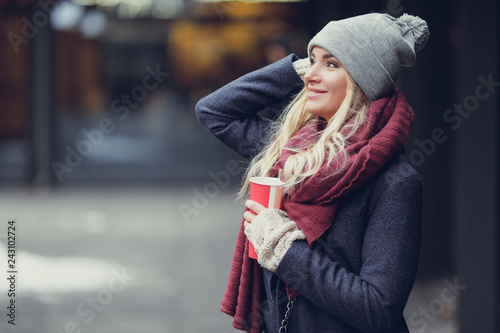 Close-up portrait of young blonde woman drinking coffe and enjoying the morning on the street. - Image