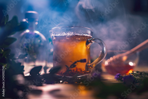 Black tea in a transparent mug, violet flowers, beautiful dark b