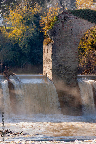 An old dam with a ruin of antique bridge over the Foglia river in Pontevecchio, Marche, Italy photo