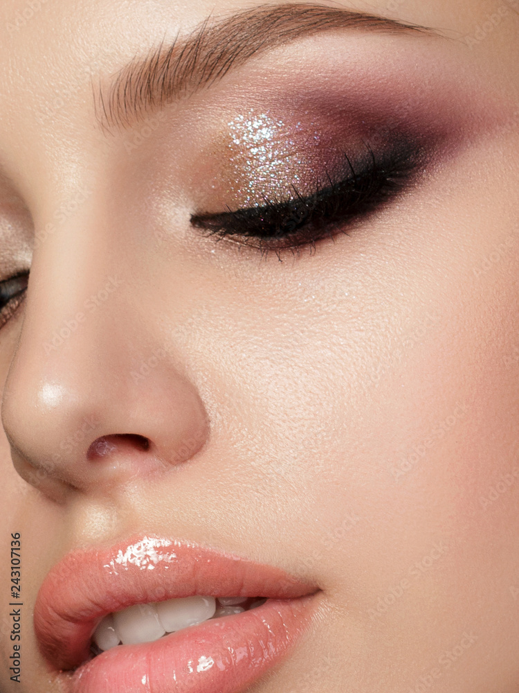 Closeup portrait of young beautiful woman with evening make up. Multicolored smokey eyes. Luxury skincare and modern fashion makeup concept. Studio shot. Extreme closeup, partial face view