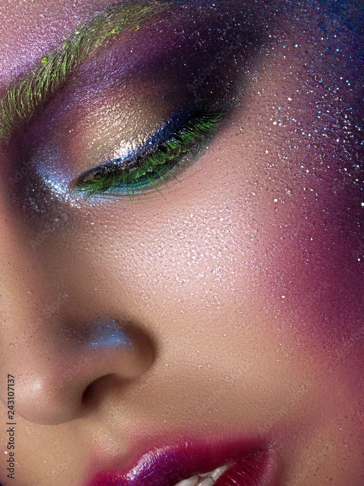 Fototapeta premium Portrait of young beautiful woman with modern fashion creative makeup. Catwalk or halloween make up. Studio shot. Extreme closeup, partial face view