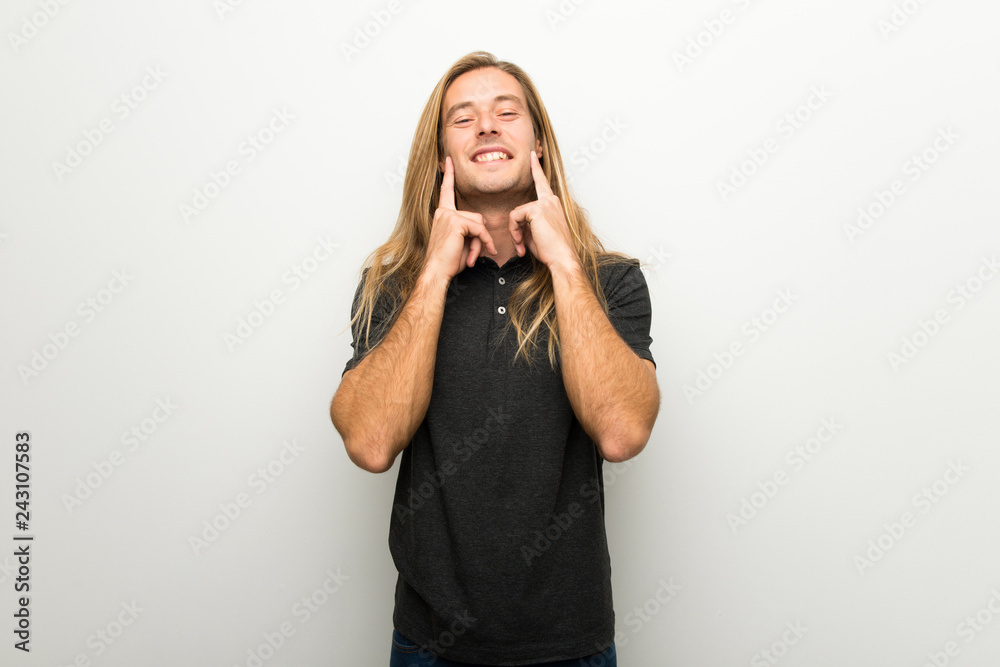 Blond man with long hair over white wall smiling with a happy and pleasant expression Blond man with long hair over white wall smiling with a happy and pleasant expression