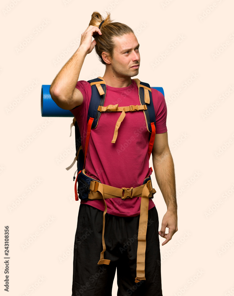 Hiker man with mountain backpacker having doubts while scratching head on isolated background Hiker man with mountain backpacker having doubts while scratching head on isolated background