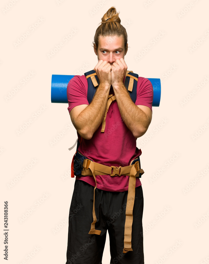 Hiker man with mountain backpacker is a little bit nervous and scared putting hands to mouth on isolated background Hiker man with mountain backpacker is a little bit nervous and scared putting hands to mouth on isolated background