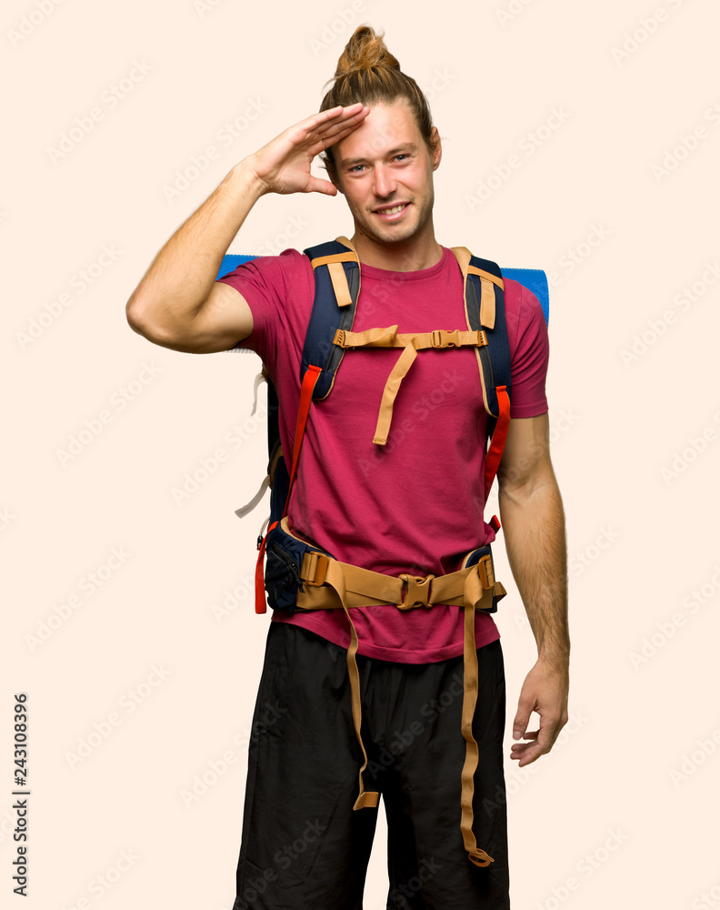 Hiker man with mountain backpacker saluting with hand on isolated background Hiker man with mountain backpacker saluting with hand on isolated background