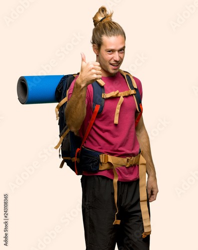 Hiker man with mountain backpacker giving a thumbs up gesture because something good has happened on isolated background