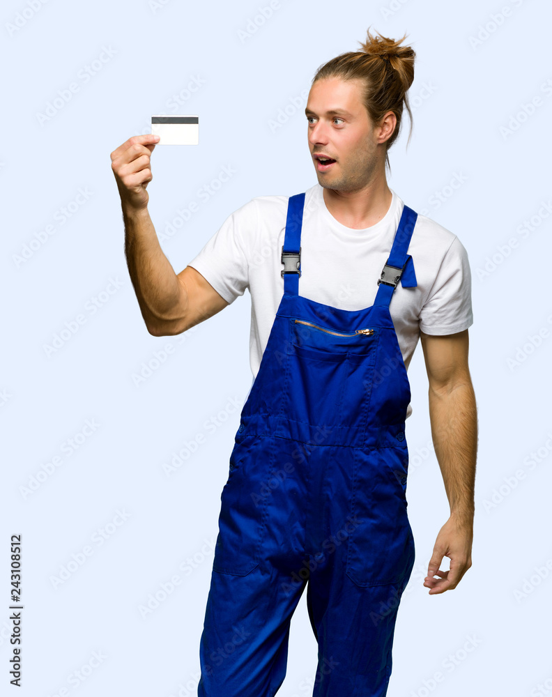 Workman holding a credit card and surprised on isolated background Workman holding a credit card and surprised on isolated background