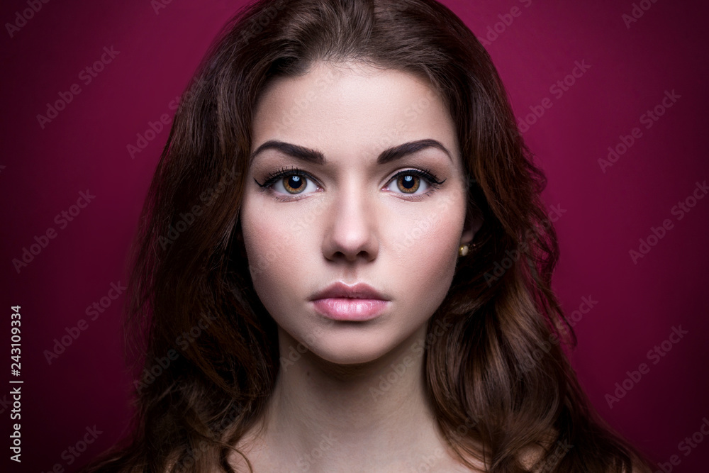 Beautiful girl looking at the camera.Shoot at studio. On a pink background. Strong face. Iris eyes. Portrait young woman. Beauty. Clean skin. Pretty model with curly hairstyle. Adult. Retouching. Beautiful girl looking at the camera.Shoot at studio. On a pink background. Strong face. Iris eyes. Portrait young woman. Beauty. Clean skin. Pretty model with curly hairstyle. Adult. Retouching.