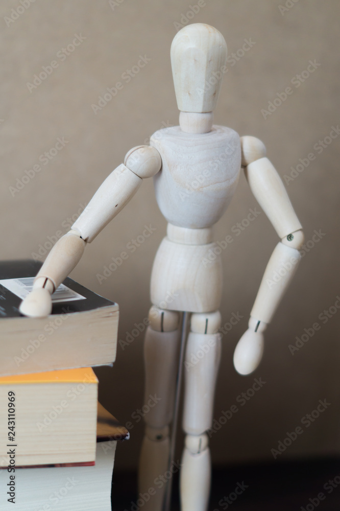 Wooden mannequin next to a stack of books. Reading concept. Wooden mannequin next to a stack of books. Reading concept.