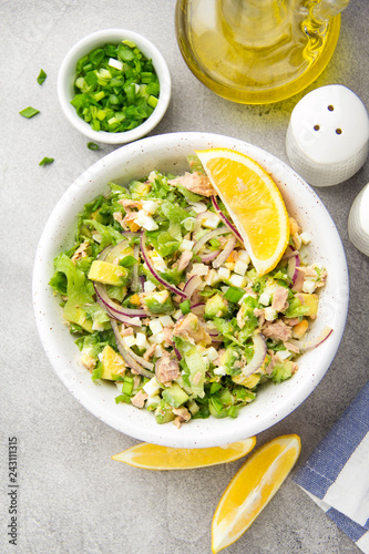 Salad with tuna, avocado, onion, egg and lemon. Spring healthy delicious lunch on light background