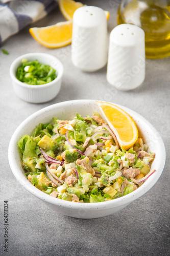 Salad with tuna, avocado, onion, egg and lemon. Spring healthy delicious lunch on light background