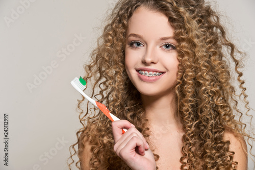 Healthy, beautiful smile, cute teen  with dental braces smiling . Portrait of a girl with orthodontic appliance. Girl brushing her teeth with toothpaste.

