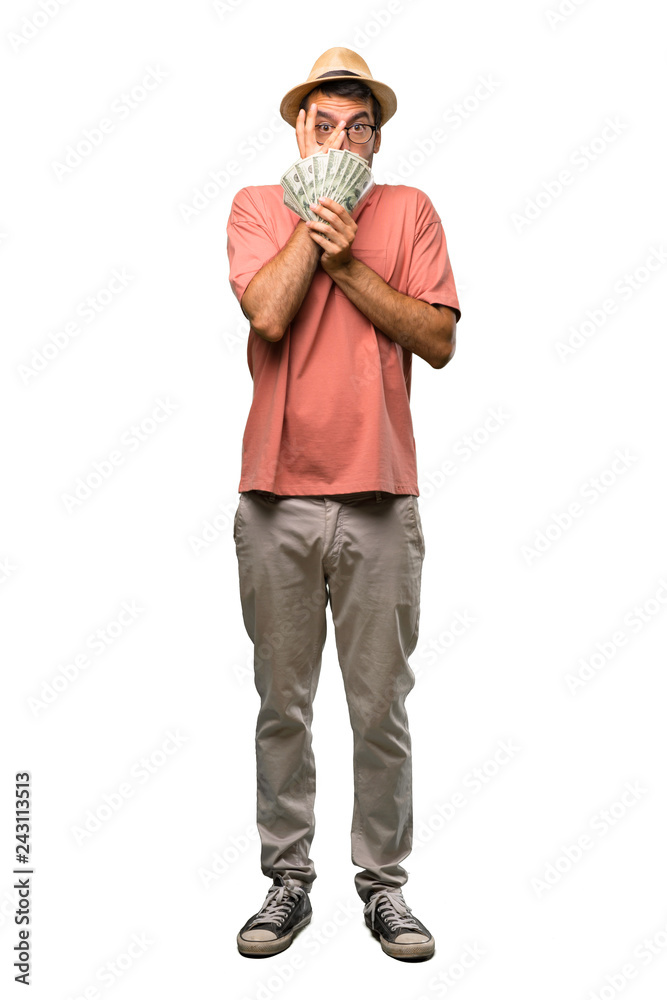 Man holding many bills surprised and covering face with hands while looking through fingers on isolated white background Man holding many bills surprised and covering face with hands while looking through fingers on isolated white background