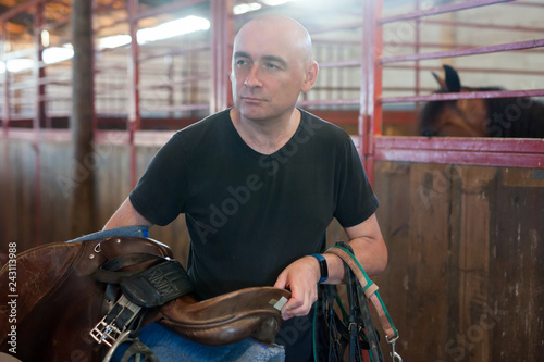 Mature man holding seats and standing at farm with horse