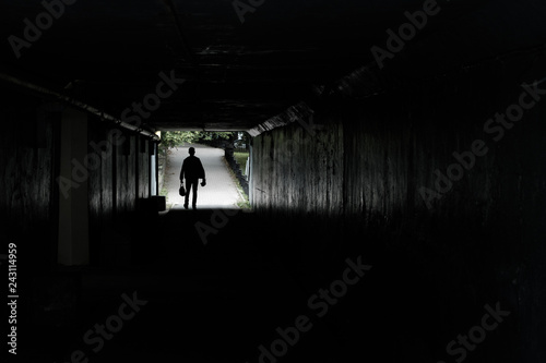 silhouette of a walking man at the end of the tunnel, in the hands of men bags and packages, background road pedestrian