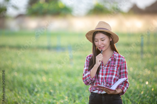 Farmers smiling women, recording happy and happy results in the onion plots with notebook