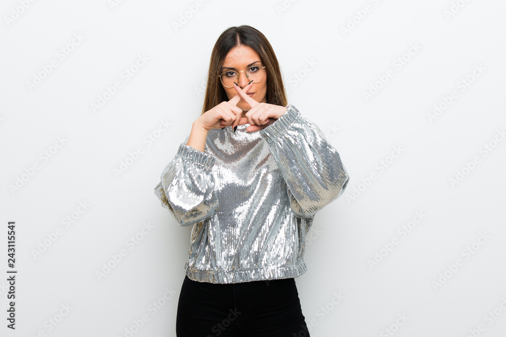 Young woman with glasses over white wall showing a sign of silence gesture Young woman with glasses over white wall showing a sign of silence gesture