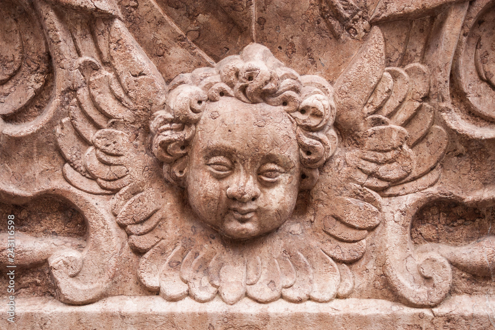 Depiction of cherub, winged unearthly christian biblical creature. Stone carved memorial plaque on the wall of Mariazellerkapelle on  St. Peter's cemetery, Salzburg, Austria