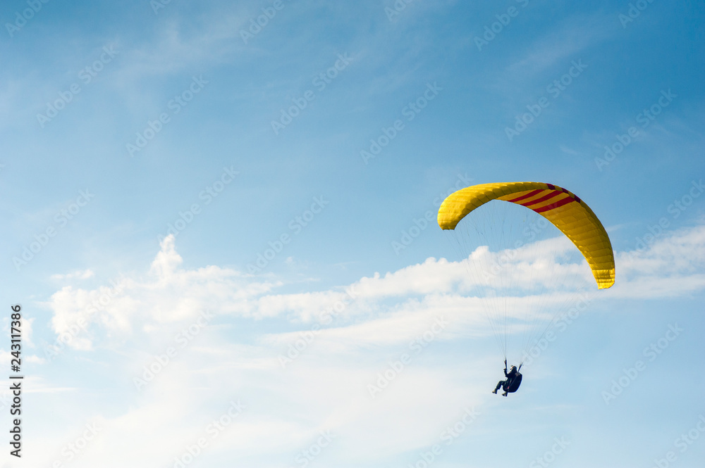Alone paraglider flying in the blue sky against the background of clouds. Paragliding in the sky on a sunny day. Alone paraglider flying in the blue sky against the background of clouds. Paragliding in the sky on a sunny day.