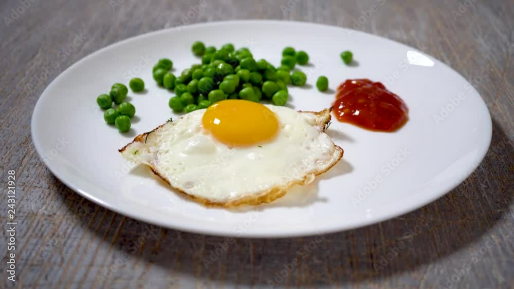 4k scrambled eggs on a white plate with peas and sauce. Top view of fried eggs eating with fork and knife. Traditional breakfast eggs eating. Morning breakfast service 4k scrambled eggs on a white plate with peas and sauce. Top view of fried eggs eating with fork and knife. Traditional breakfast eggs eating. Morning breakfast service