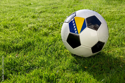 Football on a grass pitch with Bosnia Herzegovina Flag.