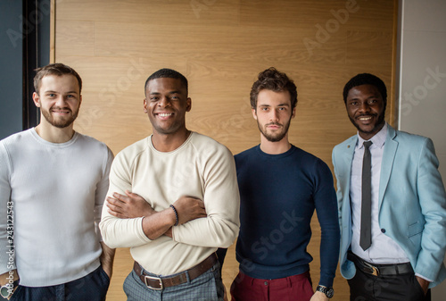 Portrait of creative business team dressed casually, standing together, being happy working together as a team. Multiracial business people together isolated over concrete wall.