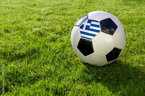 Football on a grass pitch with Greece Flag.
