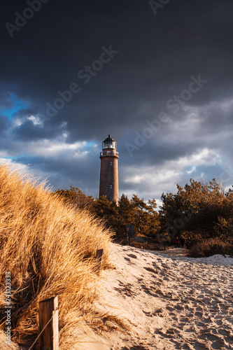 Famous landmark maritime lighthouse Darßer Ort after a winter storm with sunlight and clouds. German Baltic Sea coastline at Fischland-Darss-Zingst in Mecklenburg