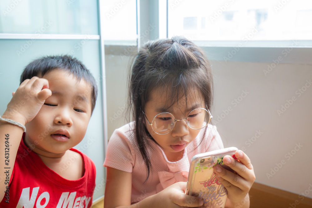 Sister and brother child playing smartphone in room Sister and brother child playing smartphone in room