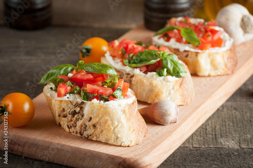 Italian tomato and cheese bruschetta. Tapas, antipasti with chopped vegetables, herbs and oil on grilled ciabatta and baguette bread.