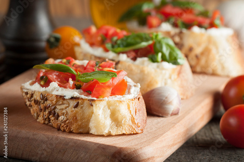 Italian tomato and cheese bruschetta. Tapas, antipasti with chopped vegetables, herbs and oil on grilled ciabatta and baguette bread.