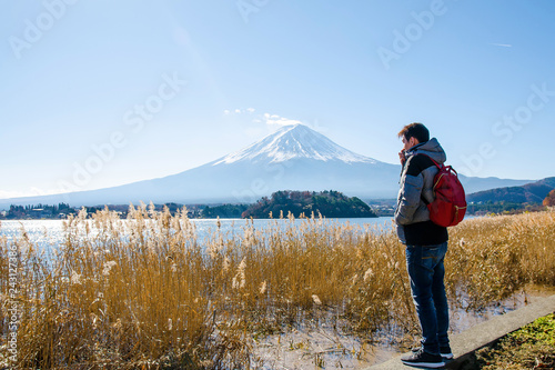 Young asian man stand looking Mount Fuji on Kawaguchiko Lake at morning