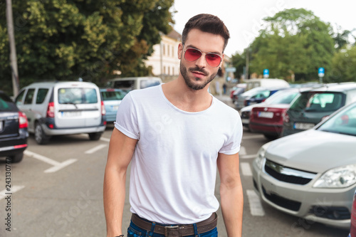portrait of casual man wearing red sunglasses standing in city