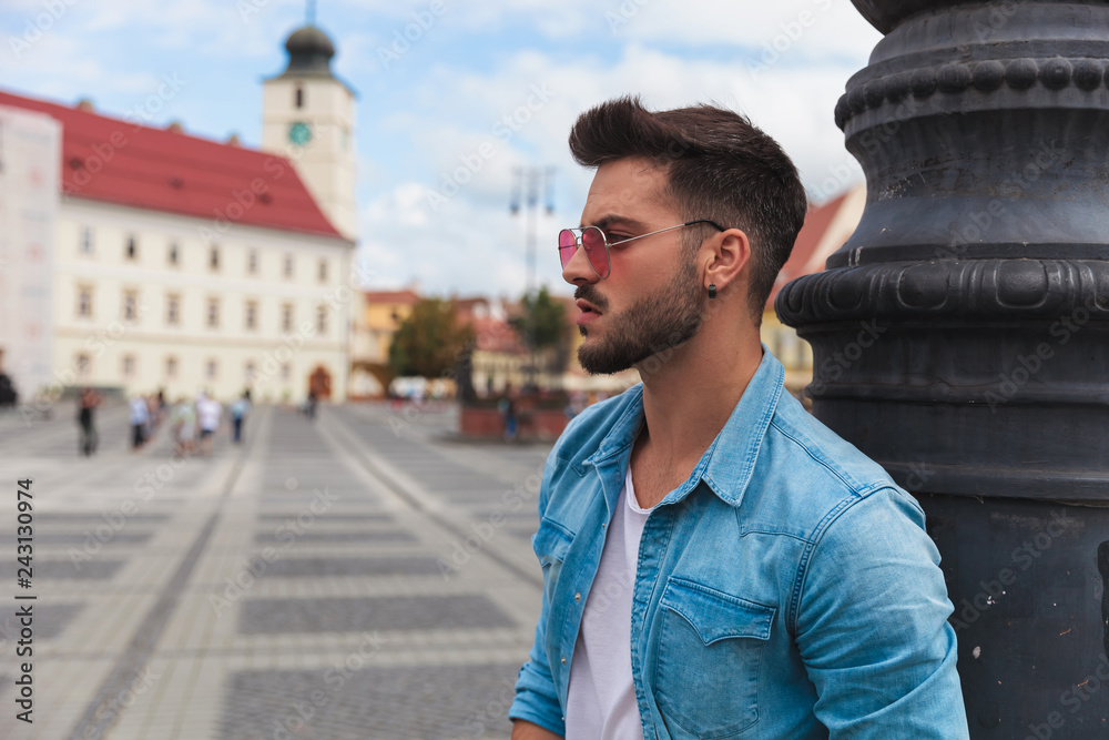 side view of sexy casual man standing near lighting pole