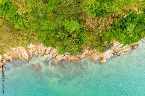 Aerial top view of ocean waves, beach and rocky coastline and beautiful forest. Beautiful nature background..