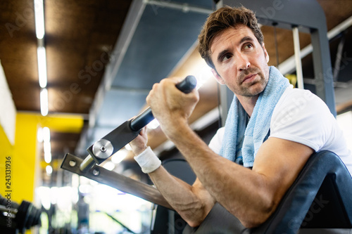 Handsome happy fit man doing exercises in gym