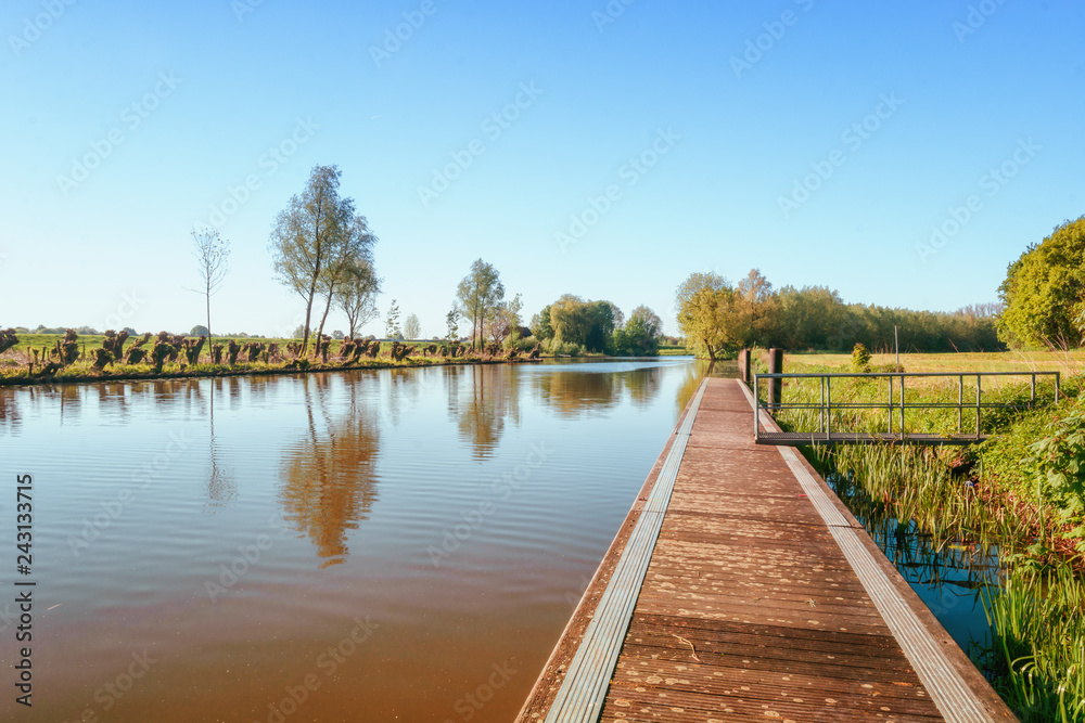 A long jetty along the river Linge in the Betuwe region with a row of cut willows on the other side
