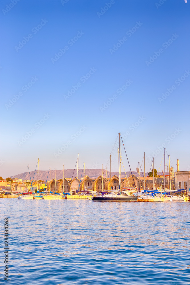 Travel Concepts. Picturesque Image of Old Venetian Harbour of Chania with line of Fisihing Boats and Yachts in the Foregound Against Clear Blue Sky in Crete, Greece.