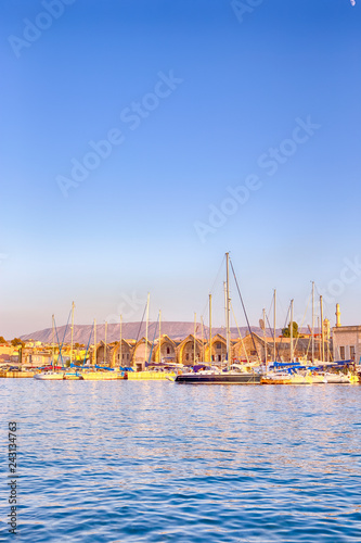 Travel Concepts. Picturesque Image of Old Venetian Harbour of Chania with line of Fisihing Boats and Yachts in the Foregound Against Clear Blue Sky in Crete, Greece.